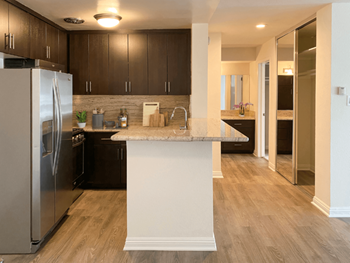 A kitchen with a refrigerator, sink, and cabinets.